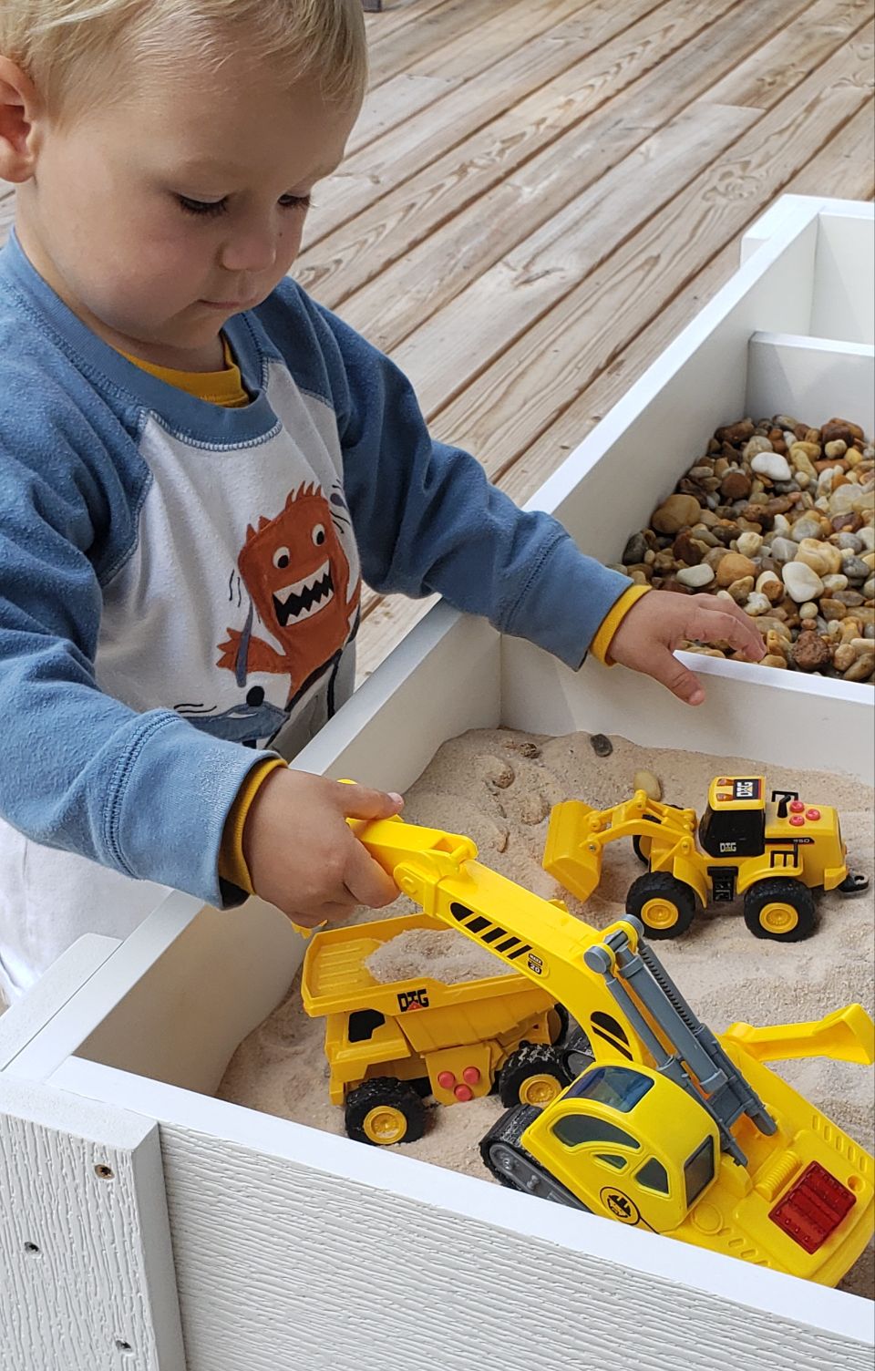 little boy playing with toys in a sandbox
